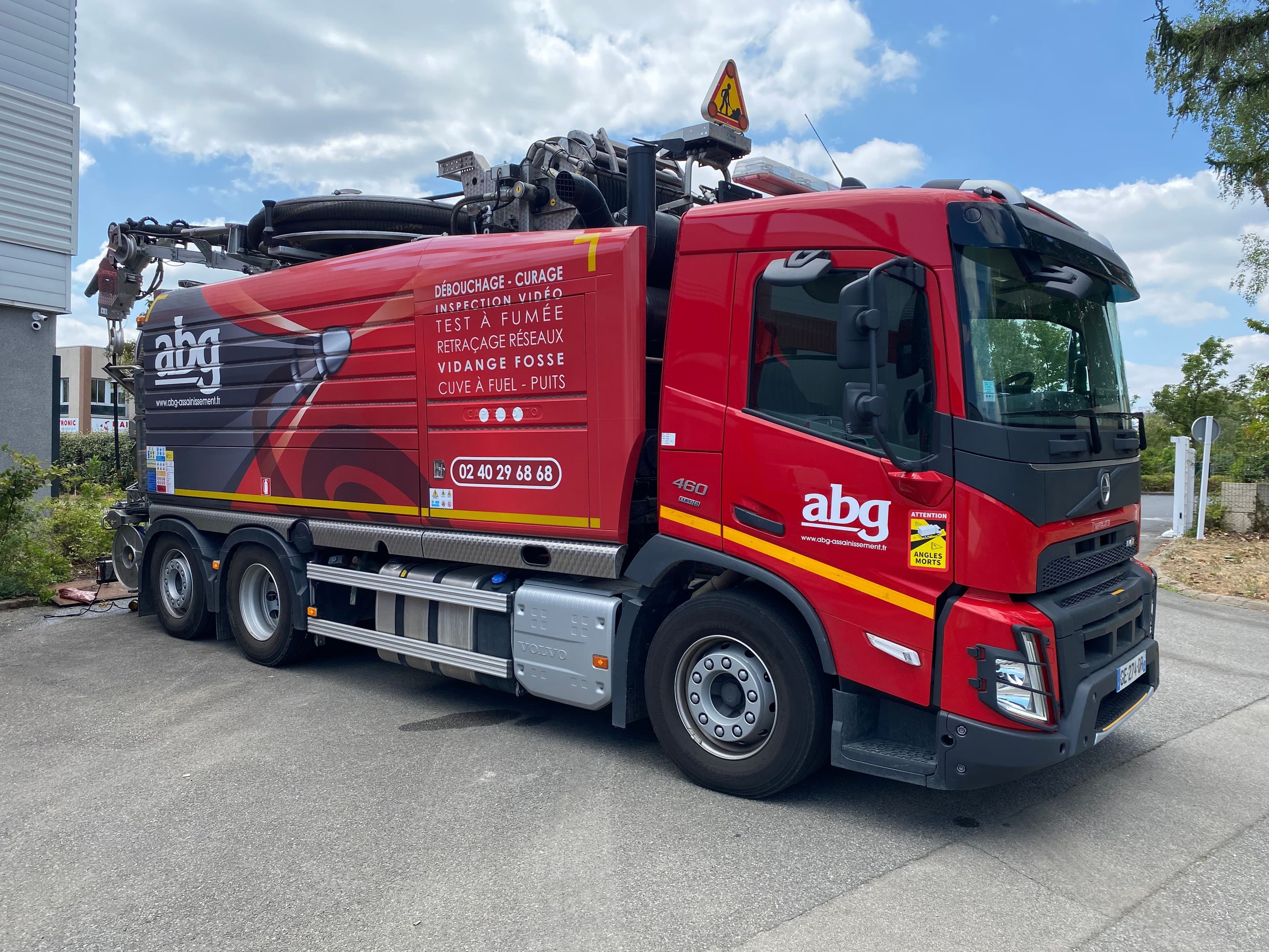 Camion hydrocureur ABG effectuant une vidange de fosse sur la voie publique en Loire Atlantique, balisage de securite en place.