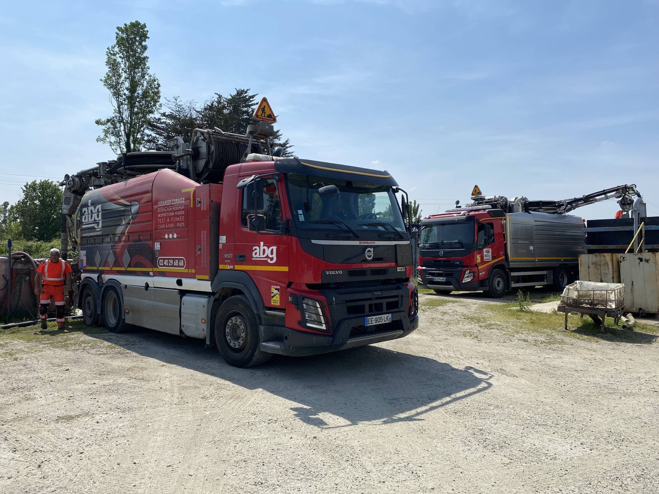 Deux camions hydrocureurs ABG en operation de vidange sur un site professionnel en Loire Atlantique avec technicien en tenue haute visibilite.